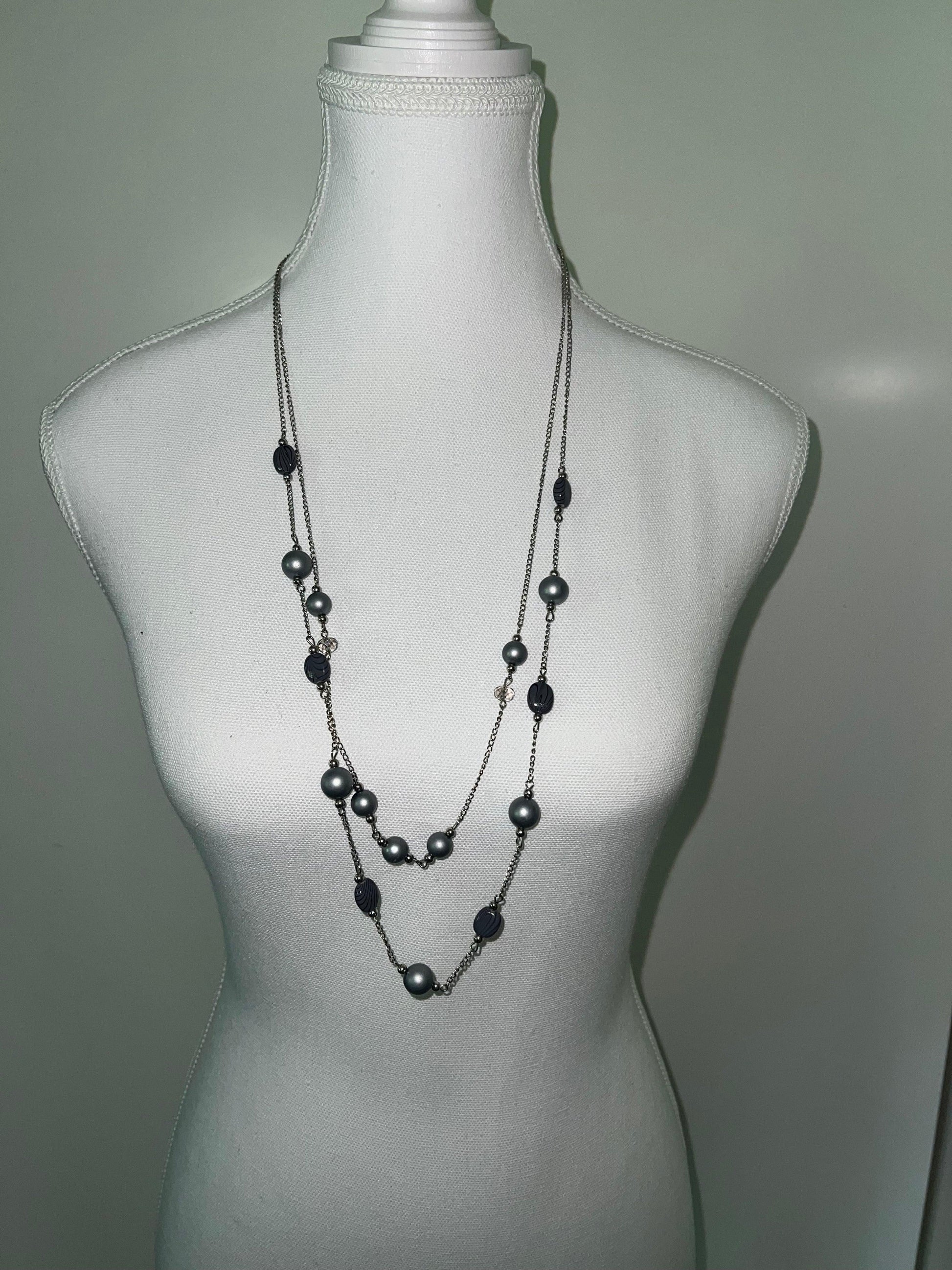 Grey double-layered beaded necklace with silver-tone chain, displayed on a white mannequin.