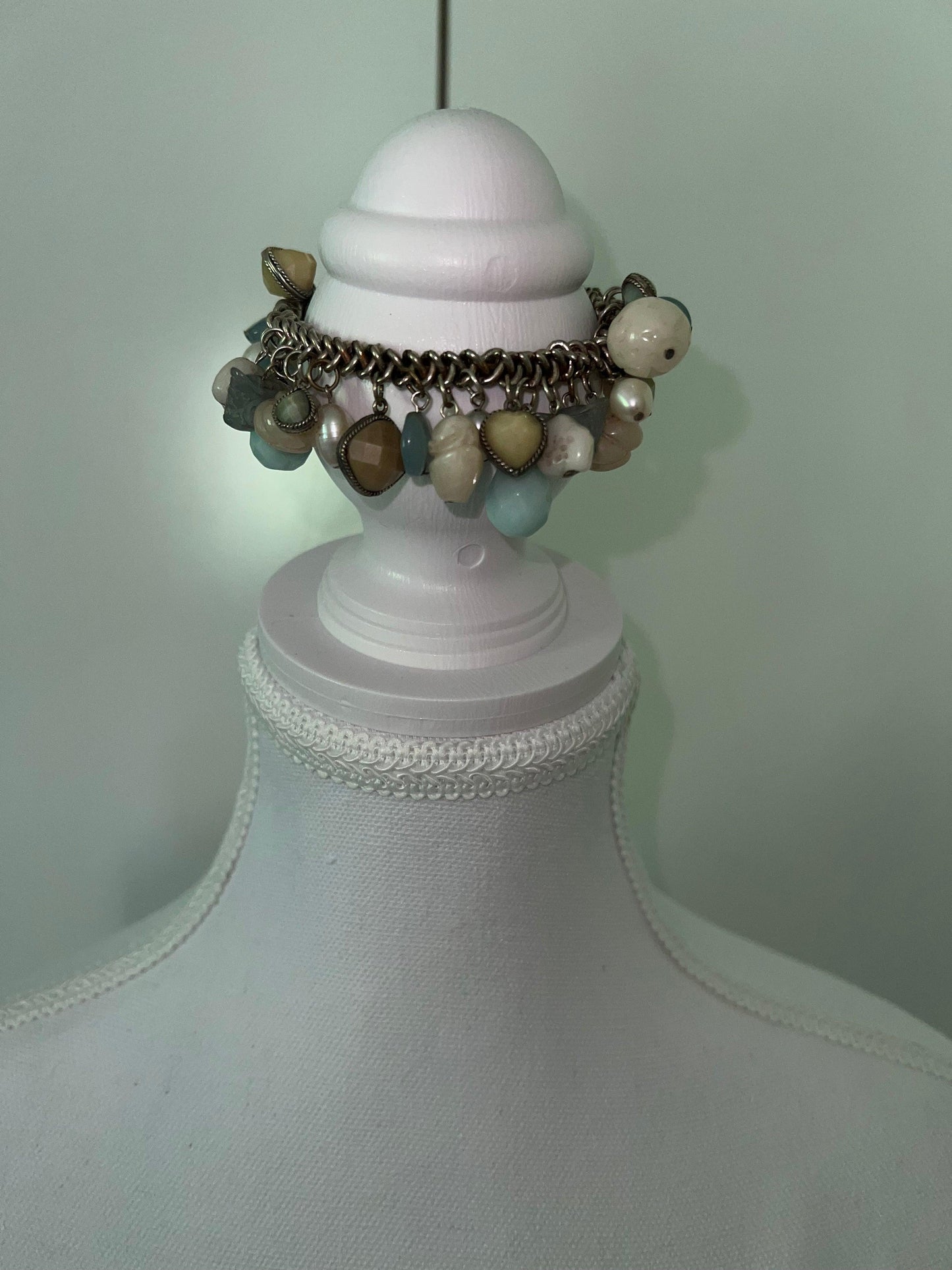 Beachy bracelet with blue, yellow, and pearl charms on a silver chain, displayed on a white mannequin.