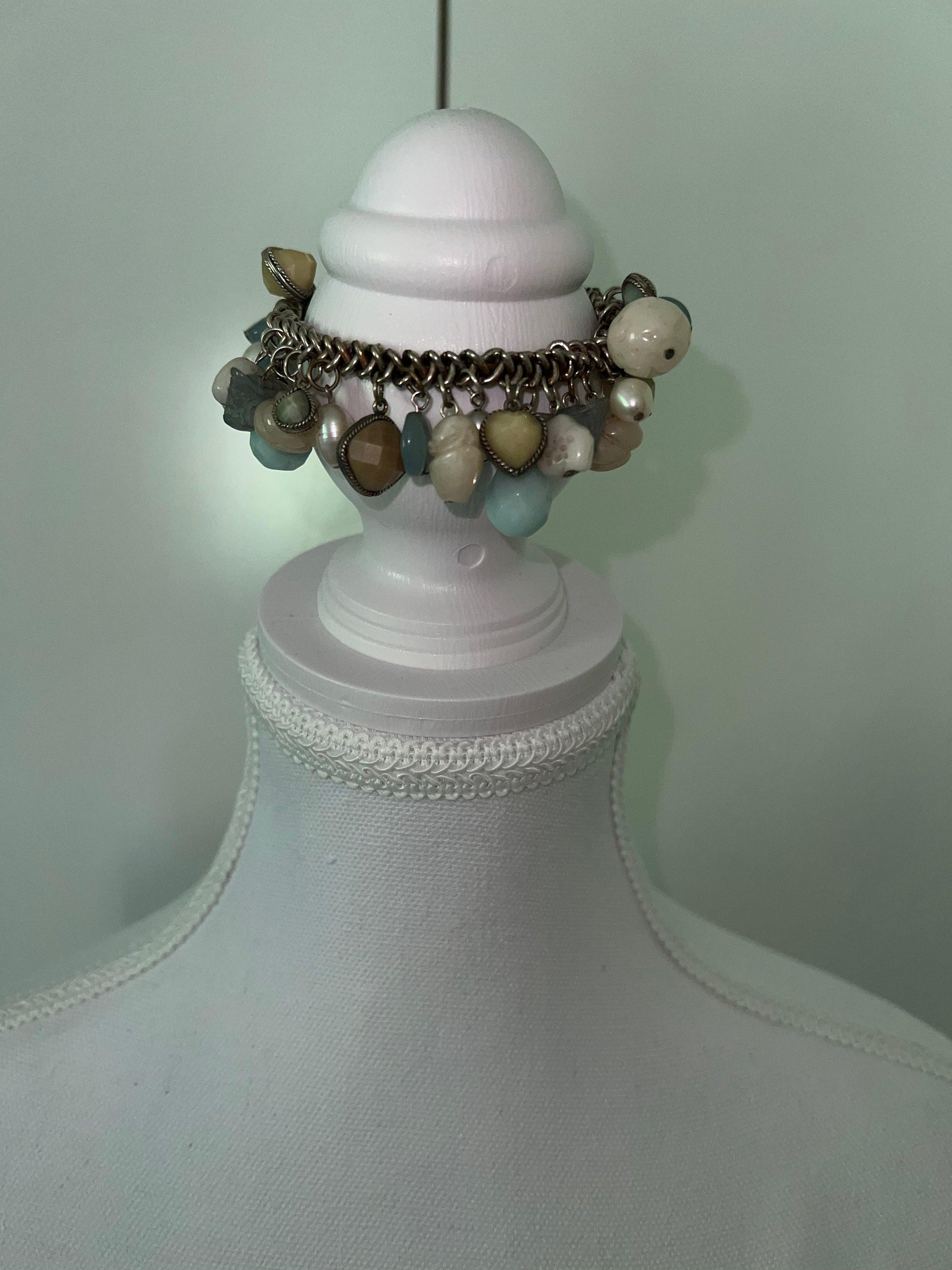 Beachy bracelet with blue, yellow, and pearl charms on a silver chain, displayed on a white mannequin.