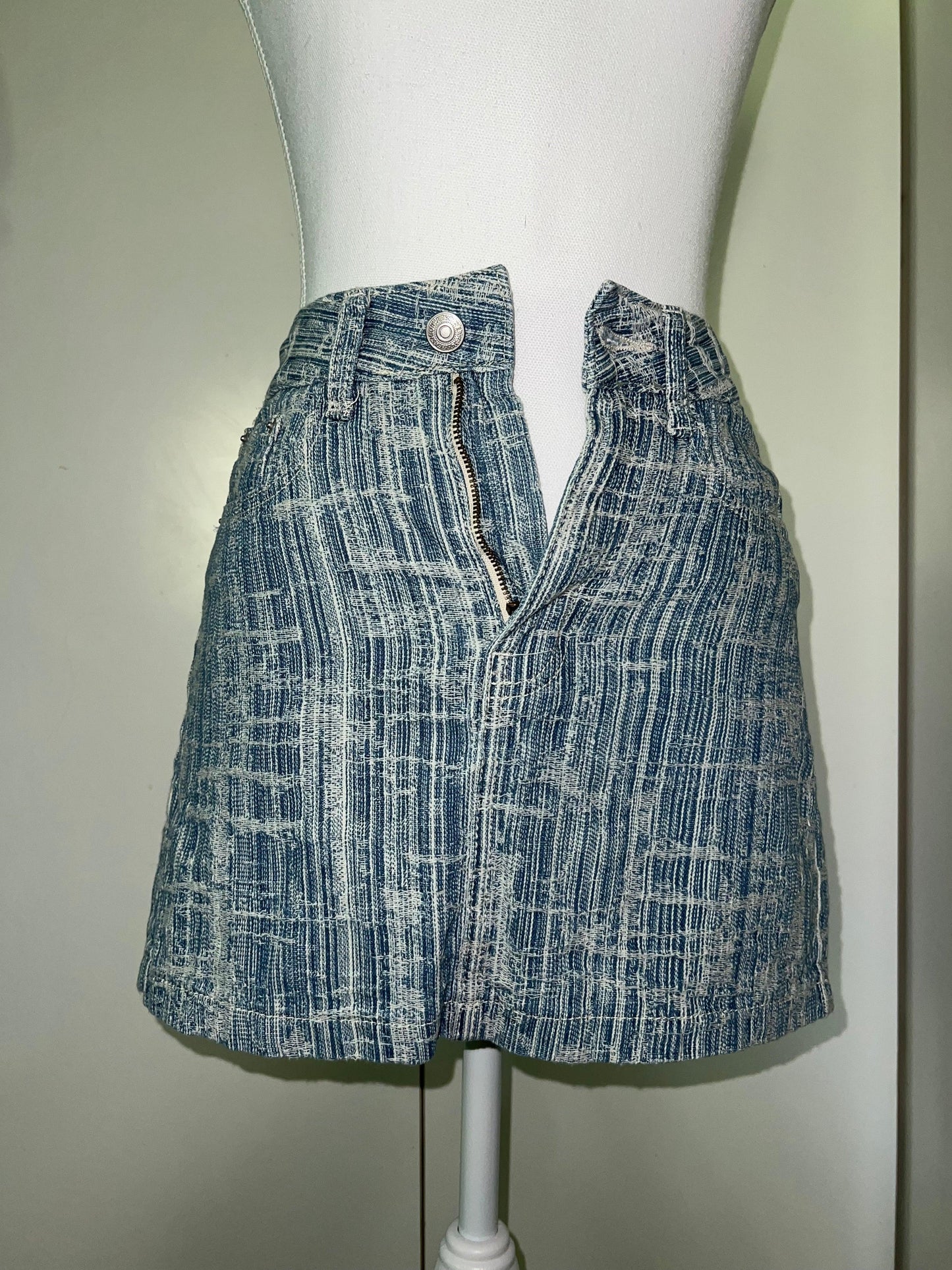 Light blue denim mini skirt with subtle white striped detail, unzipped, on a mannequin.