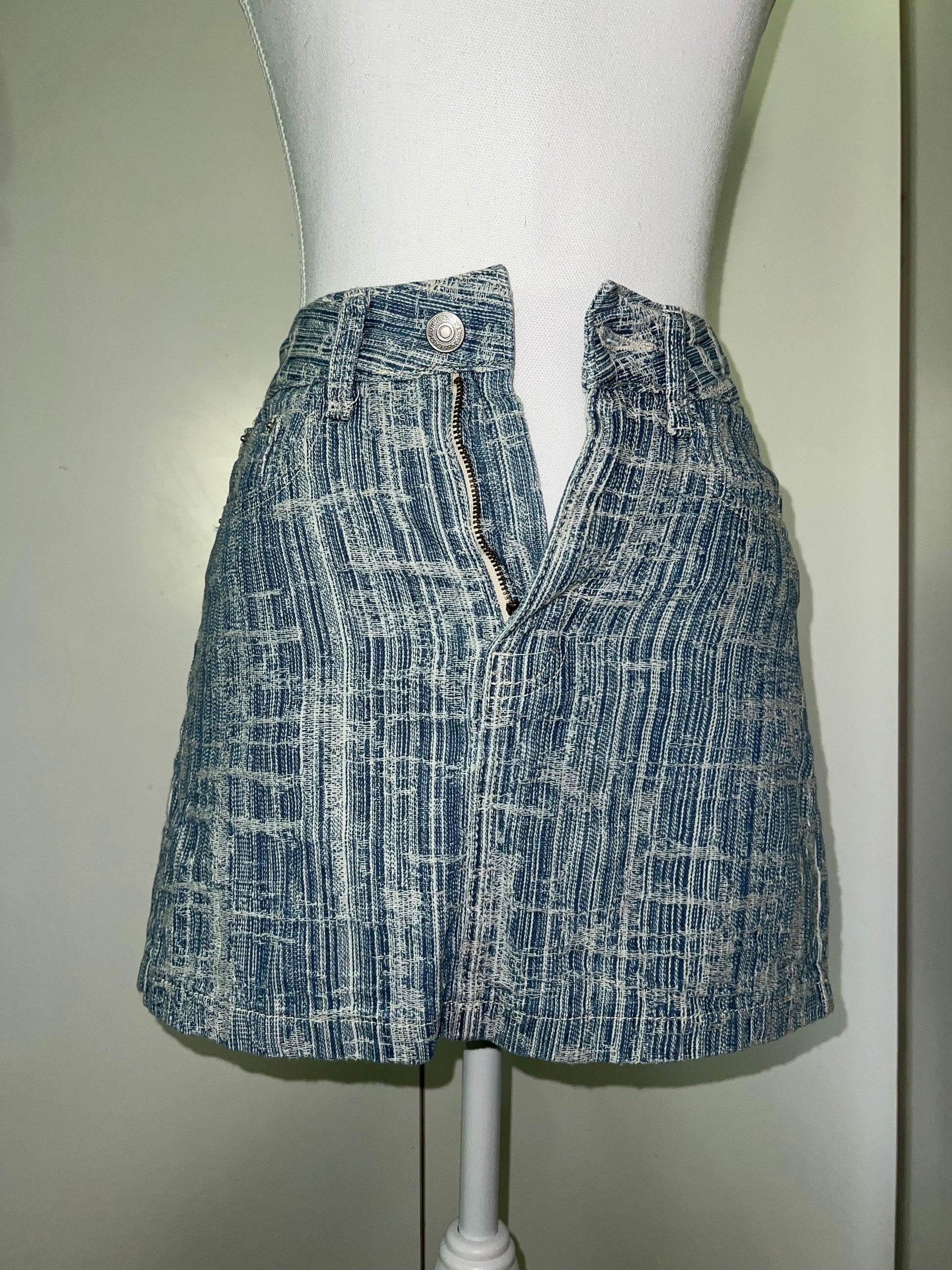 Light blue denim mini skirt with subtle white striped detail, unzipped, on a mannequin.